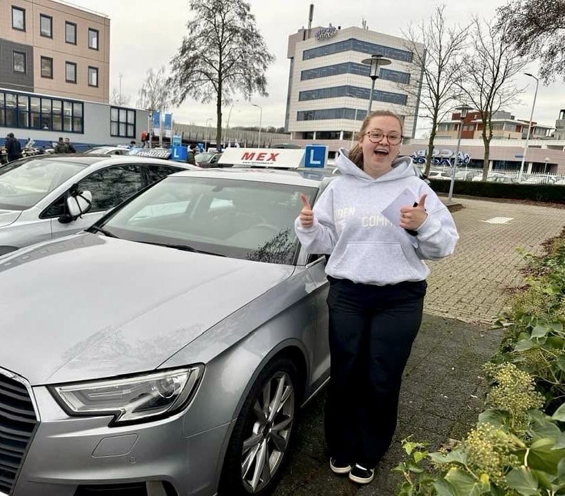 Geslaagde leerling van Rijschool MEX naast de lesauto